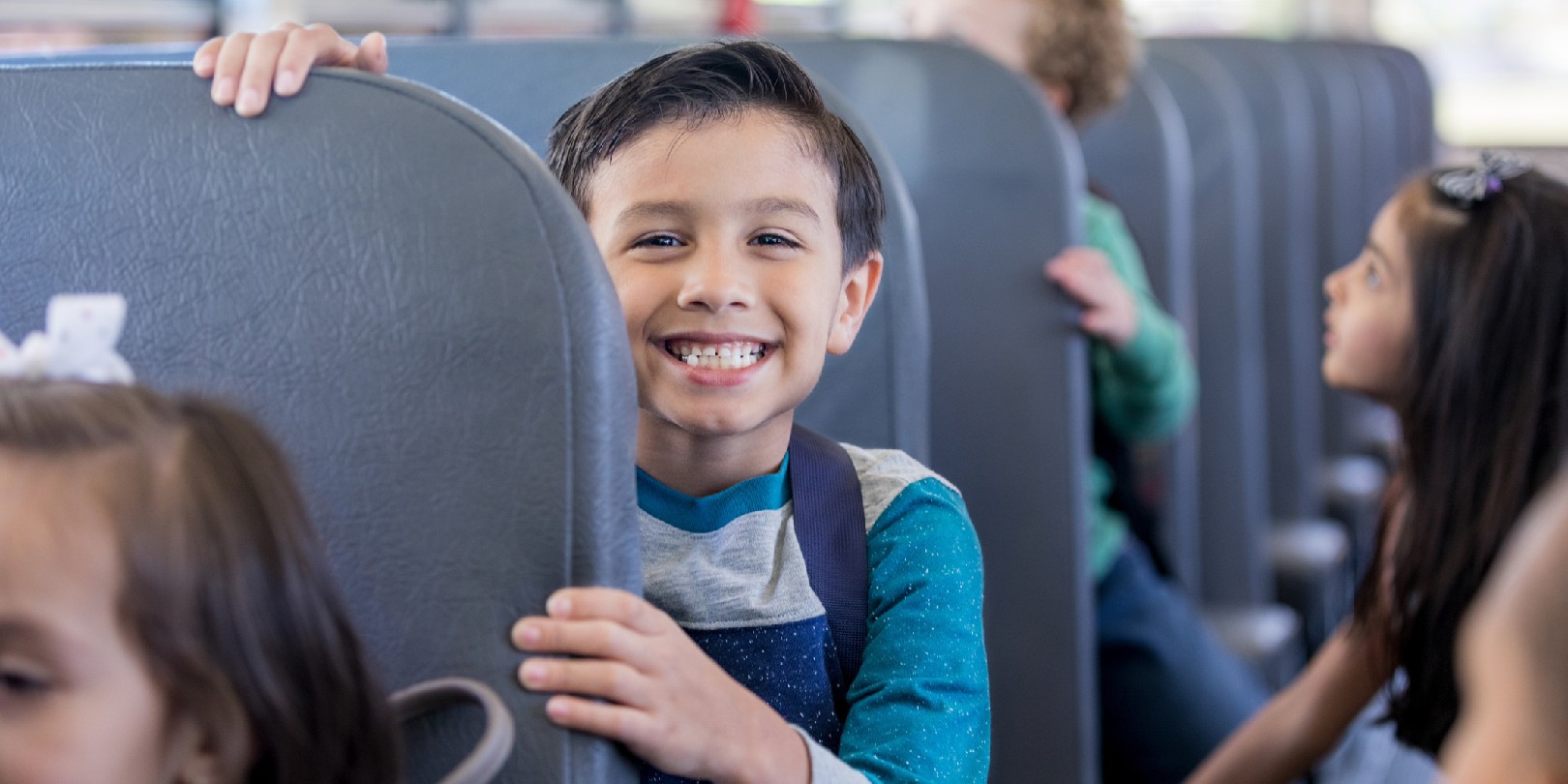 Schoolboy smiles excitedly while sitting on school bus