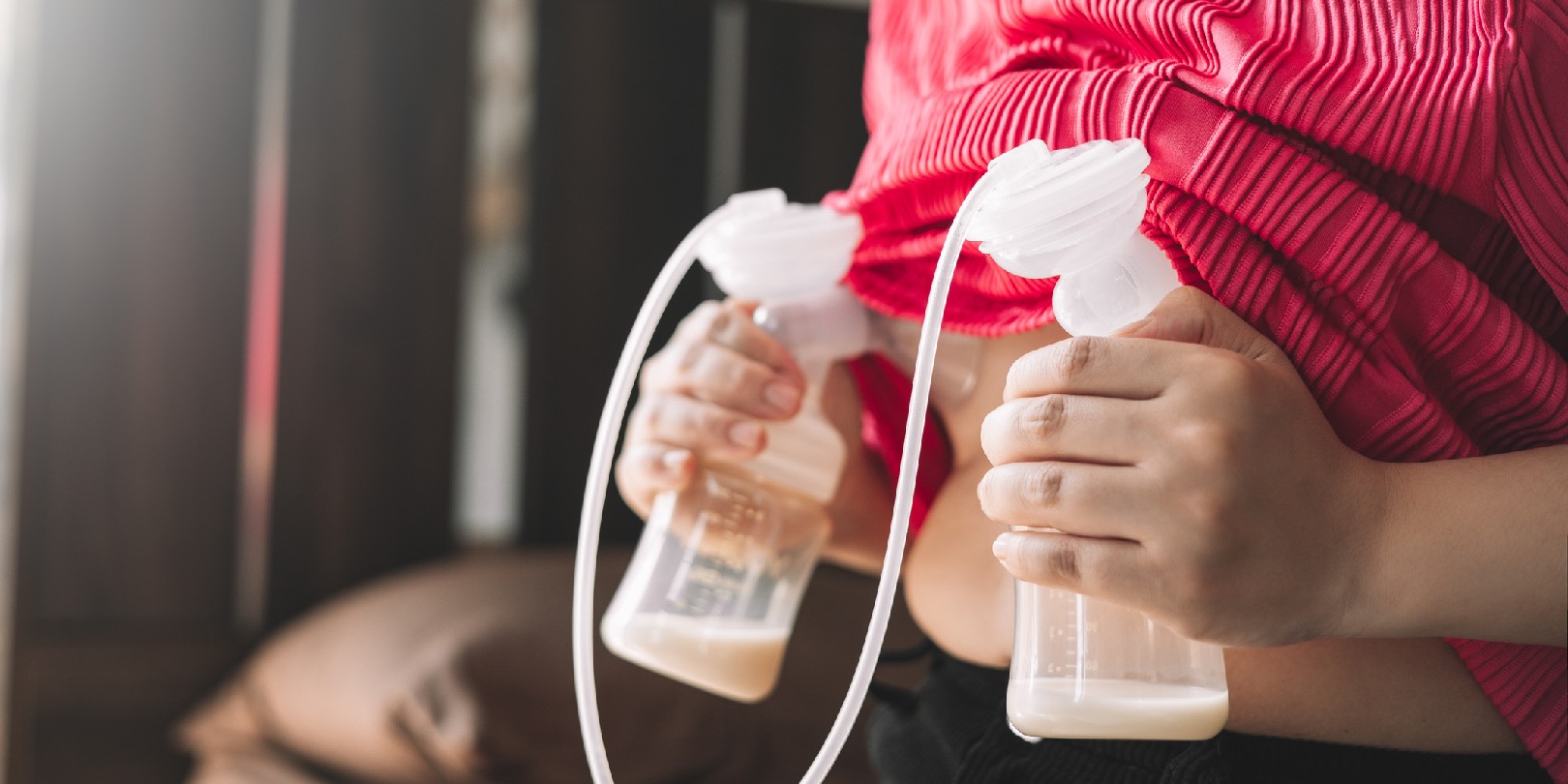 Mom using breast pump machine to pumping milk for her son in bedroom. Colostrum milk, Transitional milk, Breast Pumping milk concept.