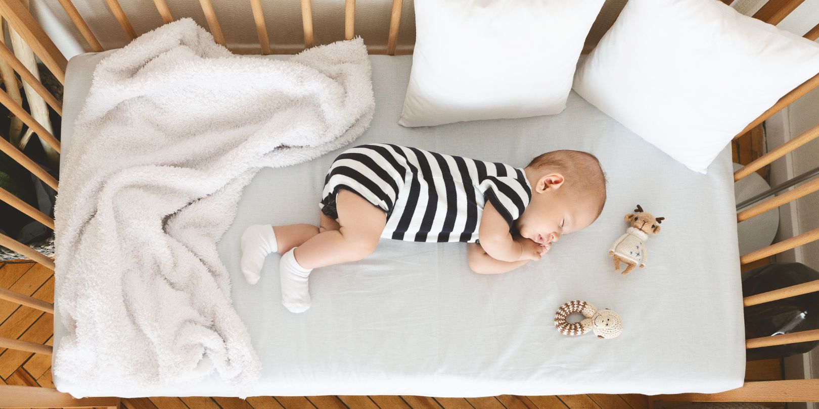 Cute infant baby napping on his side in wooden cot