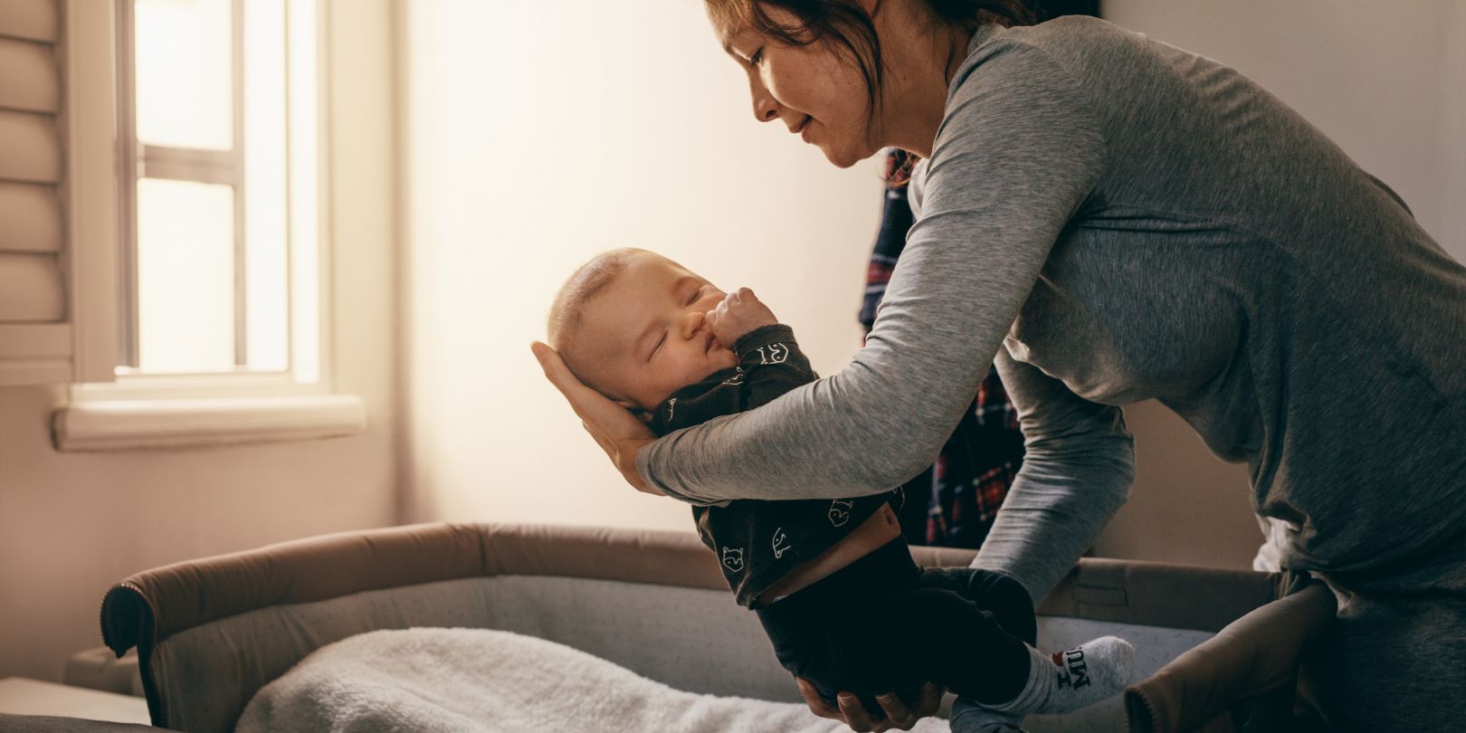 Mother Putting Her Baby to Sleep on a Bedside Baby Crib